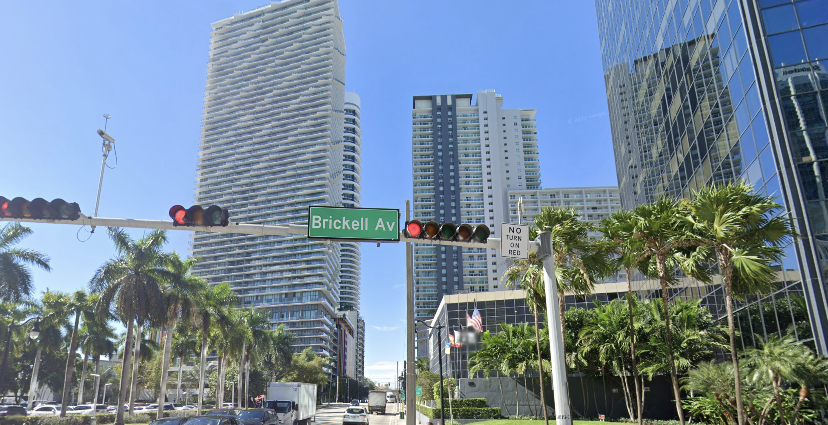 Street sign "Brickell Av" illuminated by a green light, with a tall building behind, ideal for Google Business verification in our case as our office is located on Brickell Avenue in Miami